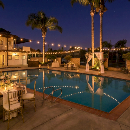 A nighttime poolside wedding setup with string lights, round dining tables, elegant chairs, floral centerpieces, and palm trees around the pool, vibe: romantic.